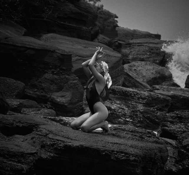 Woman in Swimwear Kneeling on Rock